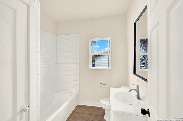 full bathroom featuring vanity, wood-type flooring, tiled shower / bath combo, and toilet