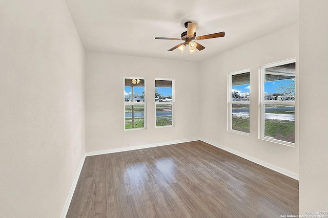 empty room with dark wood-type flooring, ceiling fan, and a healthy amount of sunlight