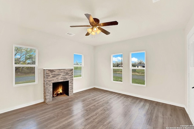 unfurnished living room with dark hardwood / wood-style floors, a stone fireplace, and ceiling fan