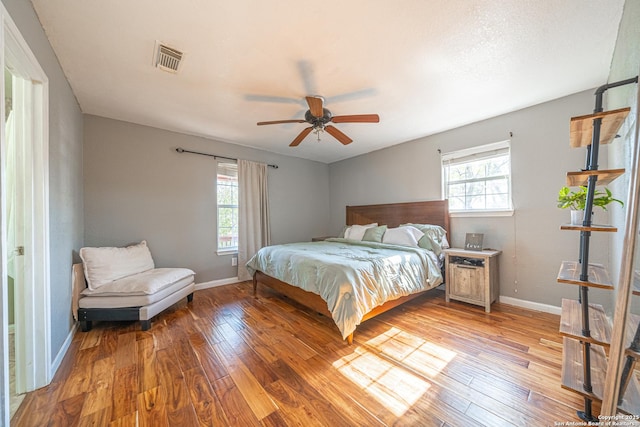 bedroom featuring hardwood / wood-style flooring, ceiling fan, and multiple windows