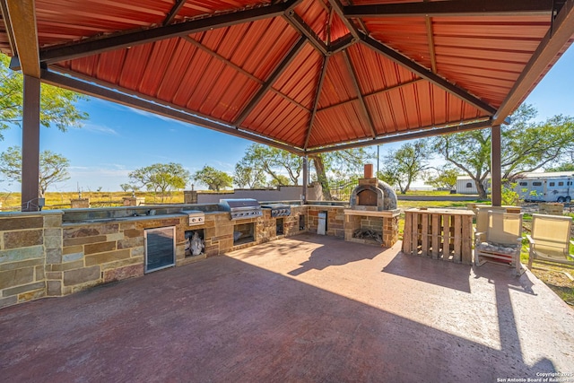 view of patio / terrace with an outdoor stone fireplace, a grill, area for grilling, and a gazebo