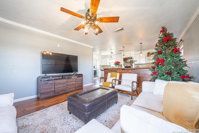 living room with washer / dryer, wood-type flooring, and crown molding