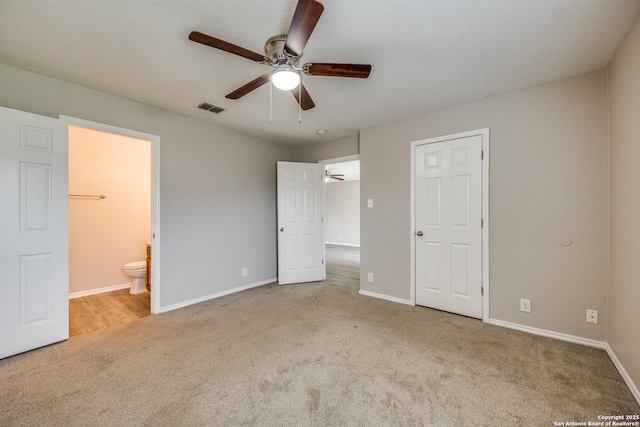 unfurnished bedroom featuring a closet, light colored carpet, ensuite bath, and ceiling fan