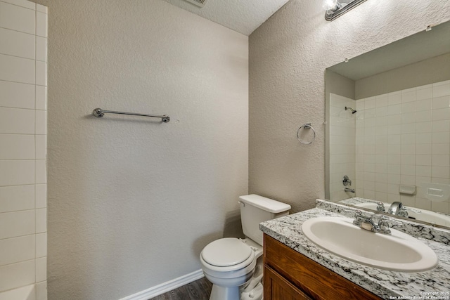 full bathroom with vanity, a textured ceiling, tiled shower / bath combo, wood-type flooring, and toilet