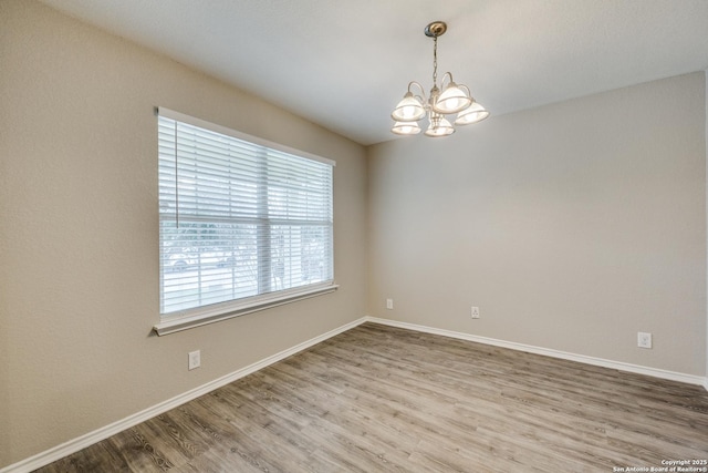 spare room featuring hardwood / wood-style flooring and an inviting chandelier