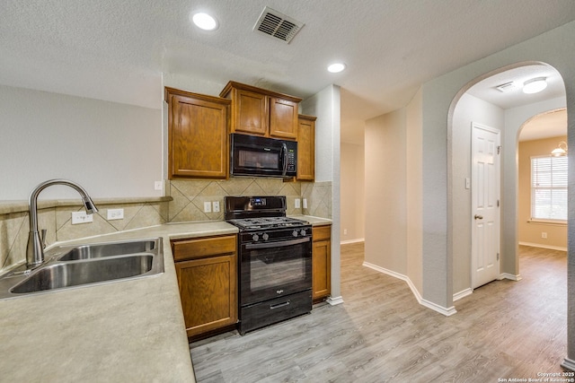 kitchen featuring black appliances, decorative backsplash, sink, and a textured ceiling