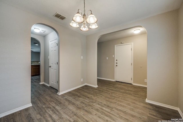 empty room with a chandelier and dark hardwood / wood-style floors