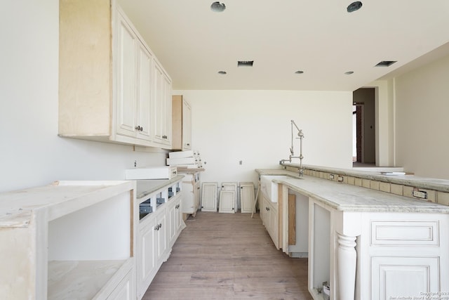 kitchen with white cabinets, sink, and light hardwood / wood-style flooring