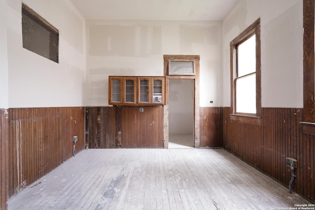 empty room with wooden walls and light hardwood / wood-style flooring