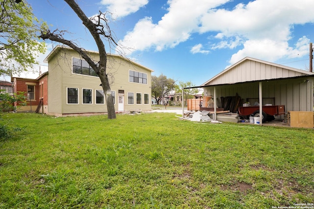 rear view of property featuring a yard and an outdoor structure