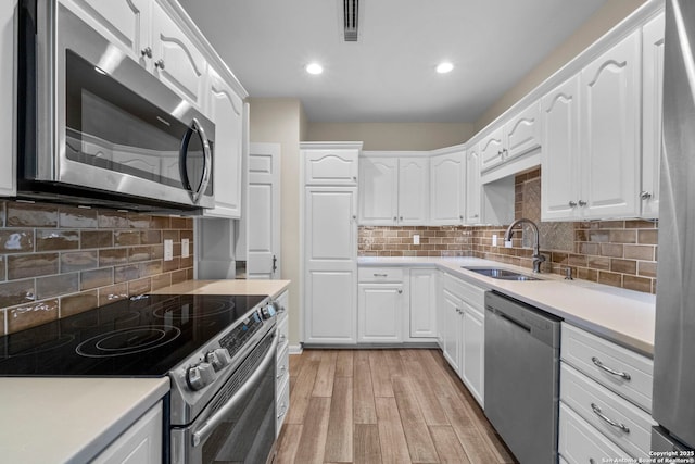 kitchen with white cabinets, appliances with stainless steel finishes, tasteful backsplash, and sink