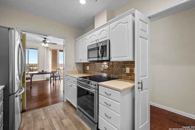 kitchen featuring white cabinets, light hardwood / wood-style flooring, ceiling fan, tasteful backsplash, and stainless steel appliances