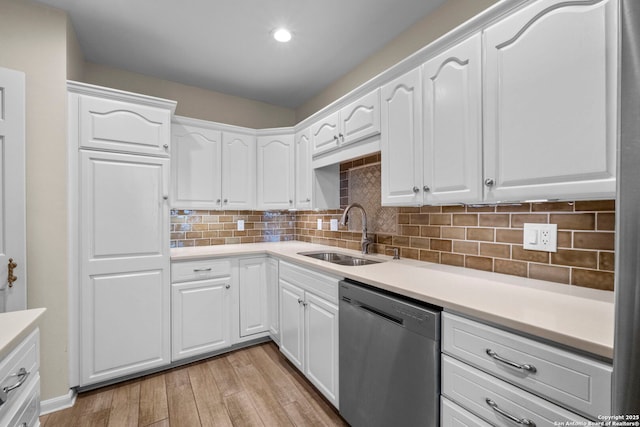 kitchen with white cabinets, sink, stainless steel dishwasher, light wood-type flooring, and tasteful backsplash