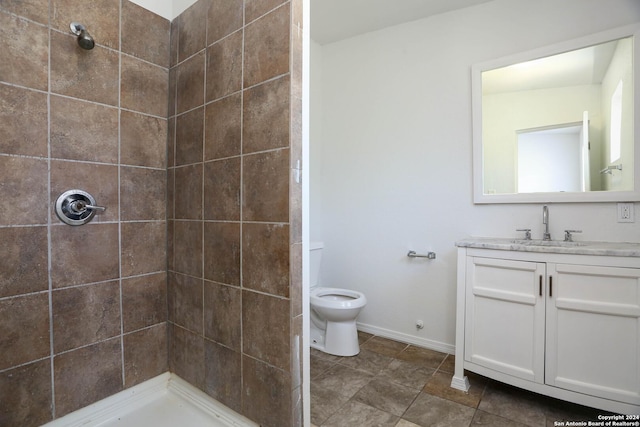 bathroom with tiled shower, vanity, and toilet