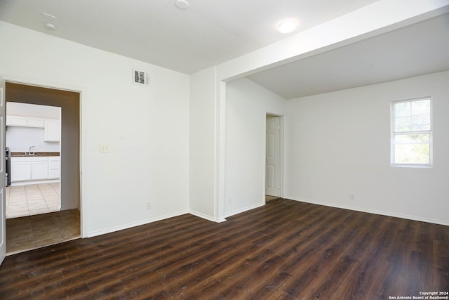 empty room with beamed ceiling, dark wood-type flooring, and sink