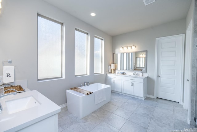 bathroom with tile patterned flooring, vanity, and a bath