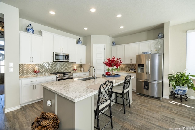 kitchen with white cabinets, an island with sink, stainless steel appliances, and sink