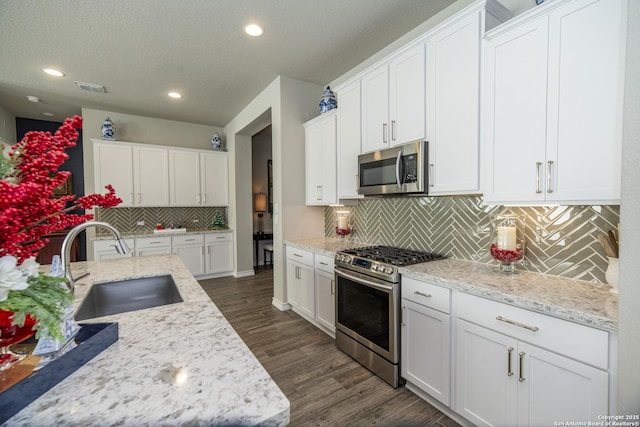 kitchen with white cabinets, sink, tasteful backsplash, light stone counters, and stainless steel appliances