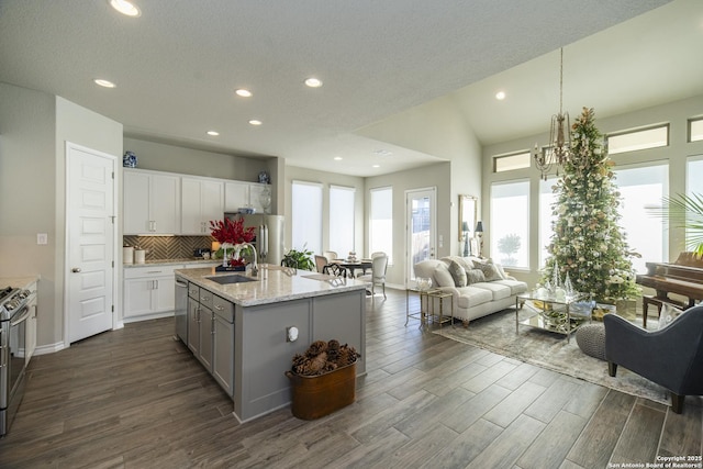 kitchen with white cabinets, sink, an island with sink, stainless steel appliances, and a chandelier