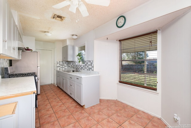 kitchen featuring sink, plenty of natural light, a textured ceiling, decorative backsplash, and white gas range oven