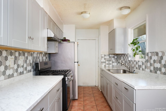 kitchen with light tile patterned floors, gray cabinets, stainless steel range with gas cooktop, and sink