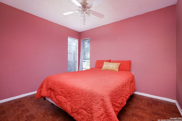 bedroom with a textured ceiling, ceiling fan, and dark parquet floors