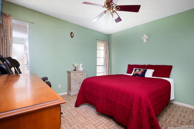 bedroom with a textured ceiling, ceiling fan, and light parquet flooring