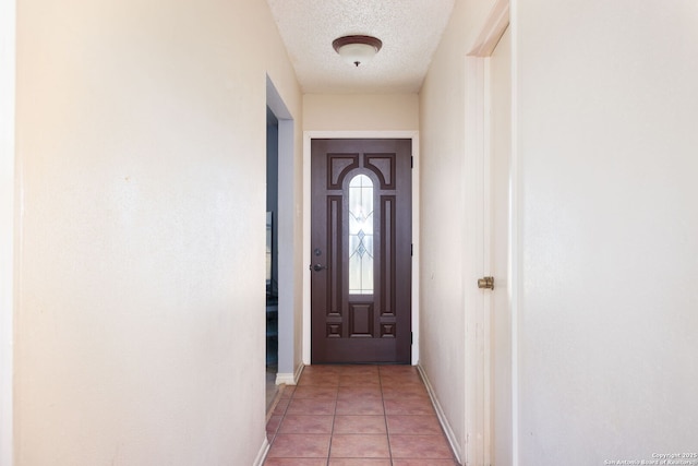 doorway to outside featuring light tile patterned floors and a textured ceiling