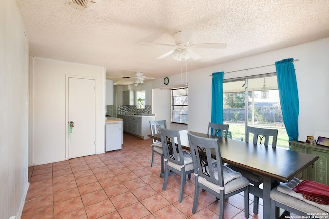 tiled dining area with ceiling fan and a textured ceiling