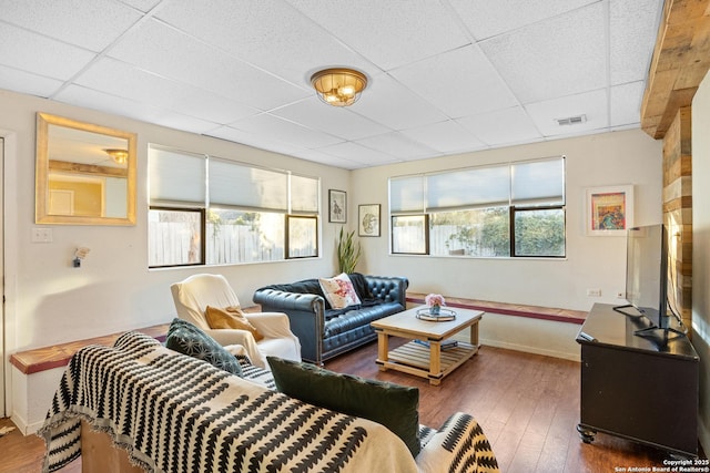 living room featuring a drop ceiling and dark wood-type flooring