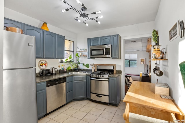 kitchen featuring blue cabinets, sink, light tile patterned floors, and appliances with stainless steel finishes