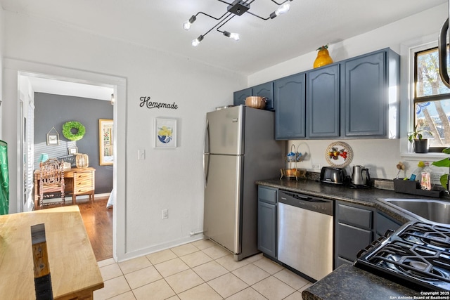 kitchen with sink, blue cabinets, light tile patterned flooring, and appliances with stainless steel finishes