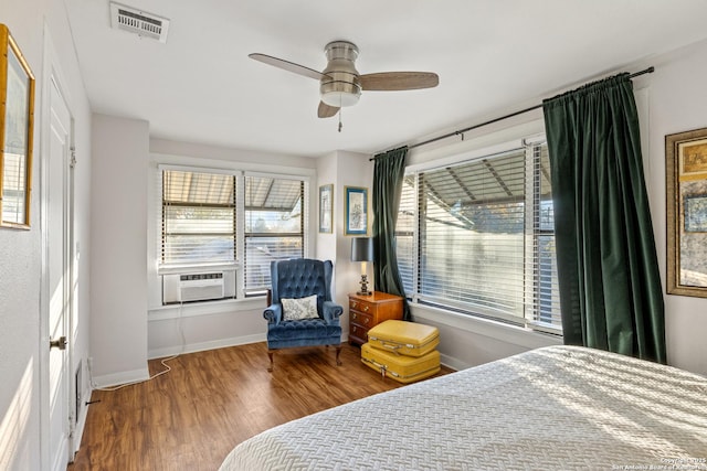 bedroom featuring ceiling fan, cooling unit, and multiple windows