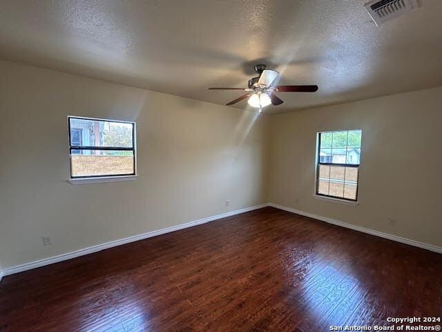 unfurnished room featuring a textured ceiling, ceiling fan, and dark wood-type flooring