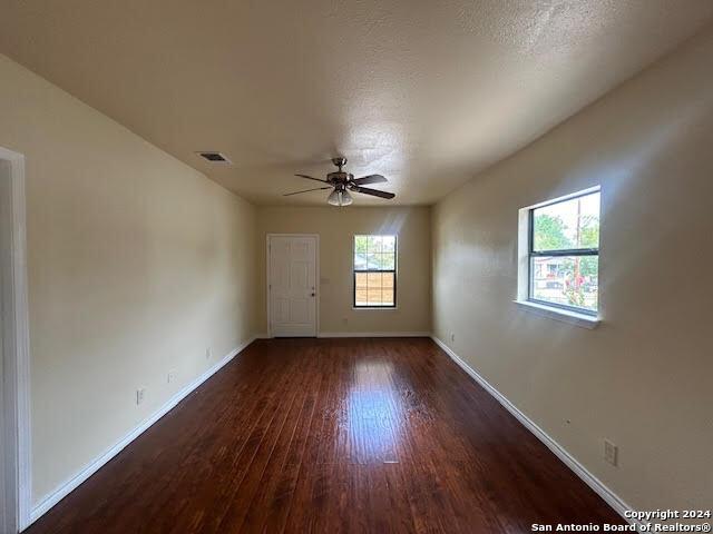 empty room with ceiling fan, dark hardwood / wood-style flooring, and a textured ceiling