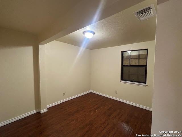 bonus room with dark hardwood / wood-style flooring and a textured ceiling