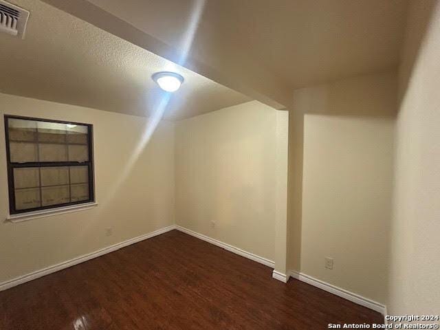 bonus room featuring a textured ceiling and dark wood-type flooring