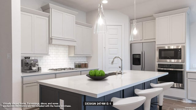 kitchen with backsplash, white cabinetry, stainless steel appliances, and a kitchen island with sink