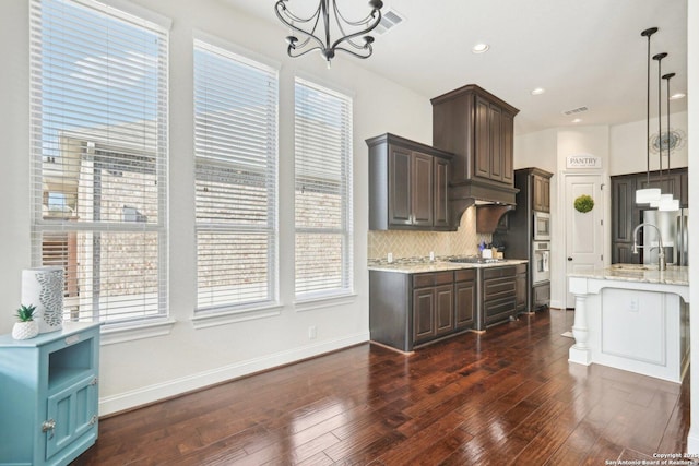 kitchen with tasteful backsplash, dark brown cabinets, pendant lighting, and appliances with stainless steel finishes