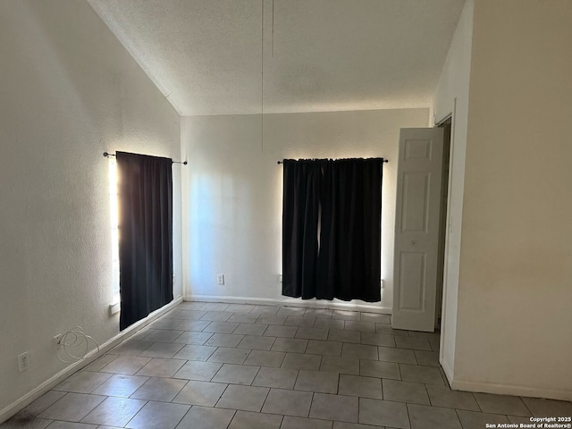 empty room featuring a textured ceiling and vaulted ceiling