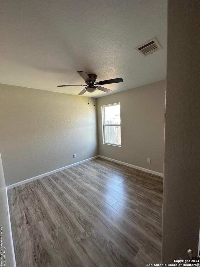 empty room with wood-type flooring, a textured ceiling, and ceiling fan