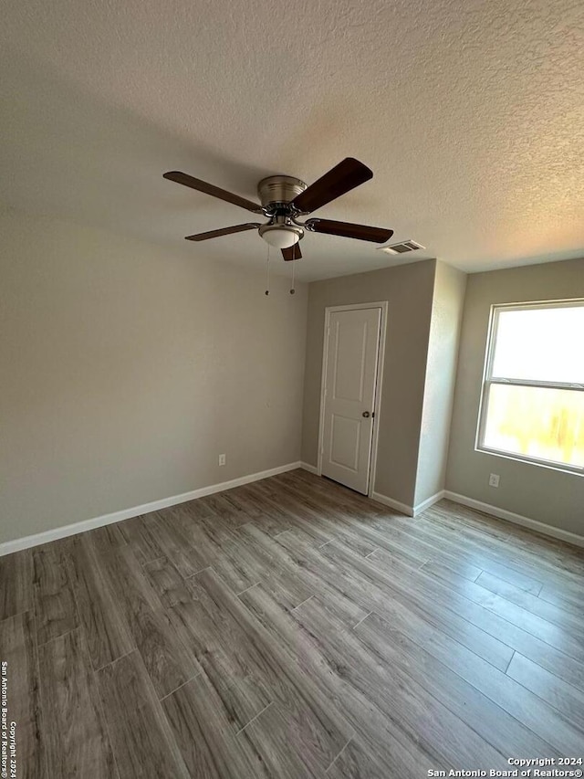 unfurnished room featuring a textured ceiling, light hardwood / wood-style flooring, and ceiling fan