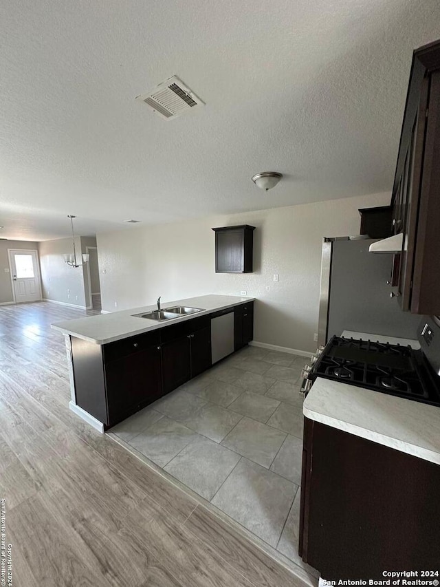 kitchen featuring gas range, dark brown cabinetry, dishwasher, and fridge