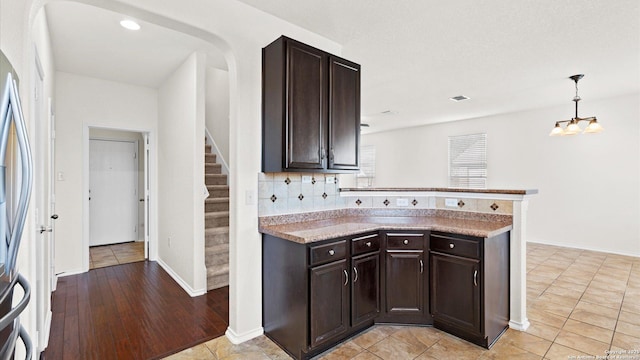 kitchen with backsplash, dark brown cabinetry, light tile patterned floors, and pendant lighting