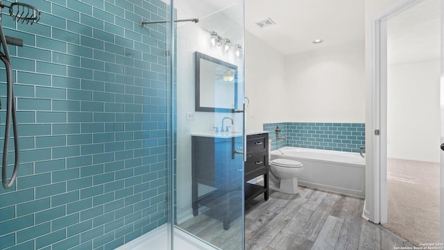 full bathroom featuring wood-type flooring, vanity, shower with separate bathtub, and toilet