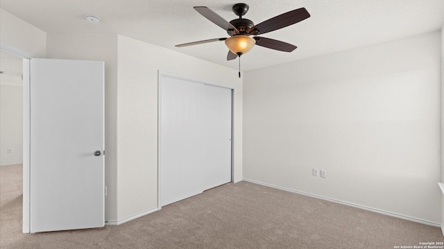 unfurnished bedroom with ceiling fan, a closet, and light carpet