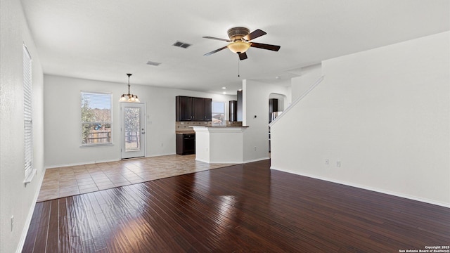 unfurnished living room with wood-type flooring and ceiling fan with notable chandelier