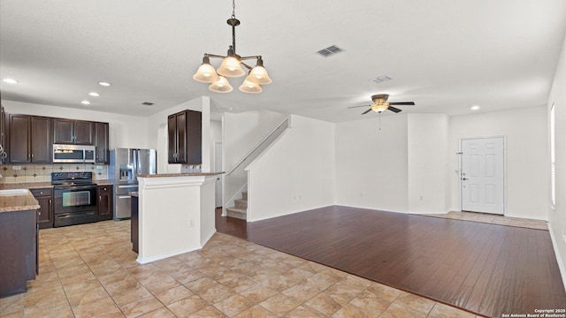 kitchen with ceiling fan with notable chandelier, hanging light fixtures, decorative backsplash, dark brown cabinets, and stainless steel appliances