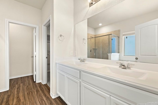 bathroom with hardwood / wood-style floors, vanity, and a shower with shower door