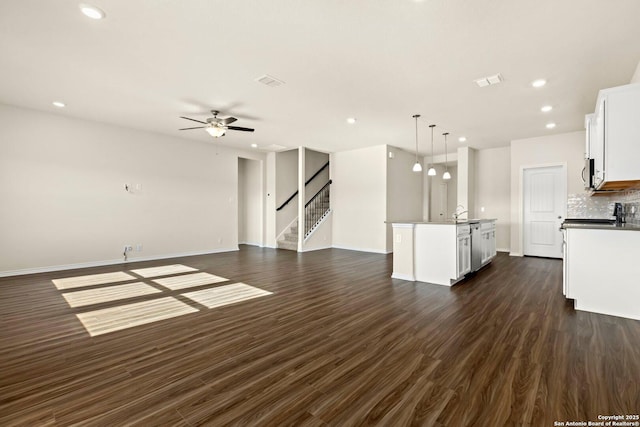 unfurnished living room with ceiling fan and dark hardwood / wood-style flooring